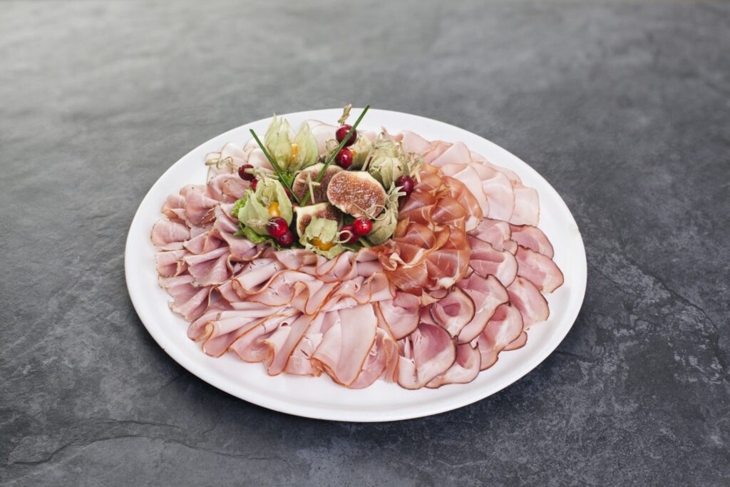 Teller mit verschiedenen Schinkensorten und Salatgarnierung